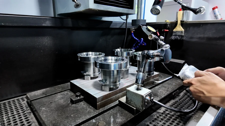 Mold components positioned in an EDM setup beside a dial indicator