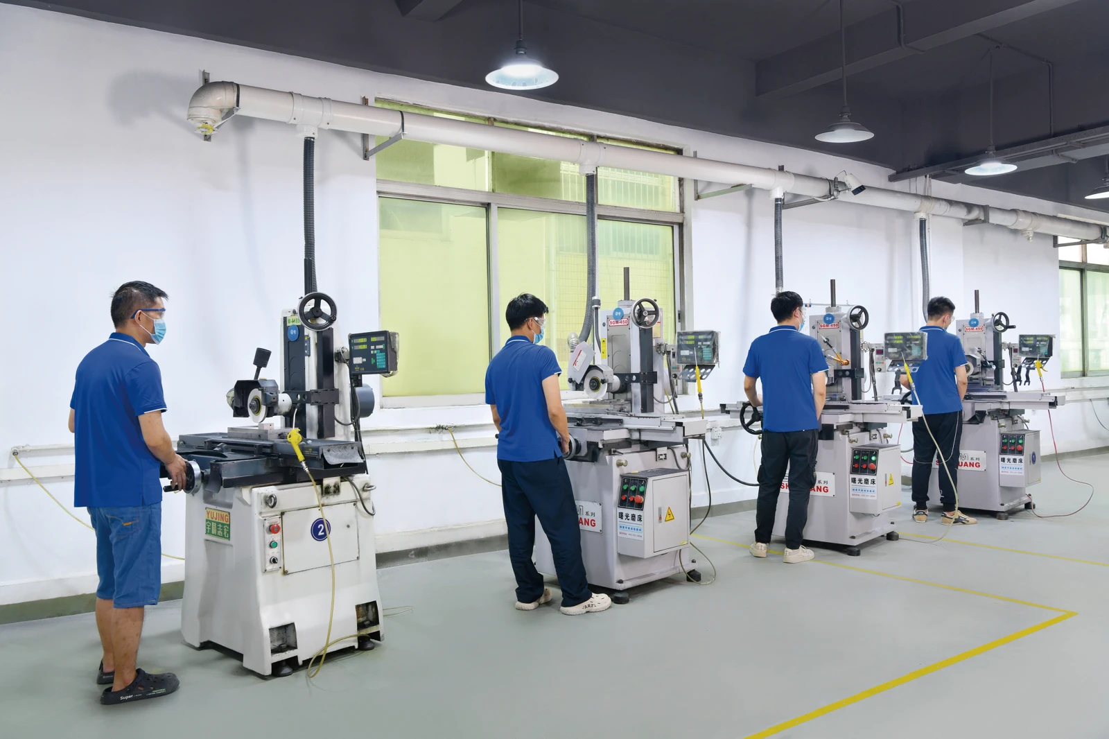 Operators at precision surface grinding workstations in the SENLAN workshop