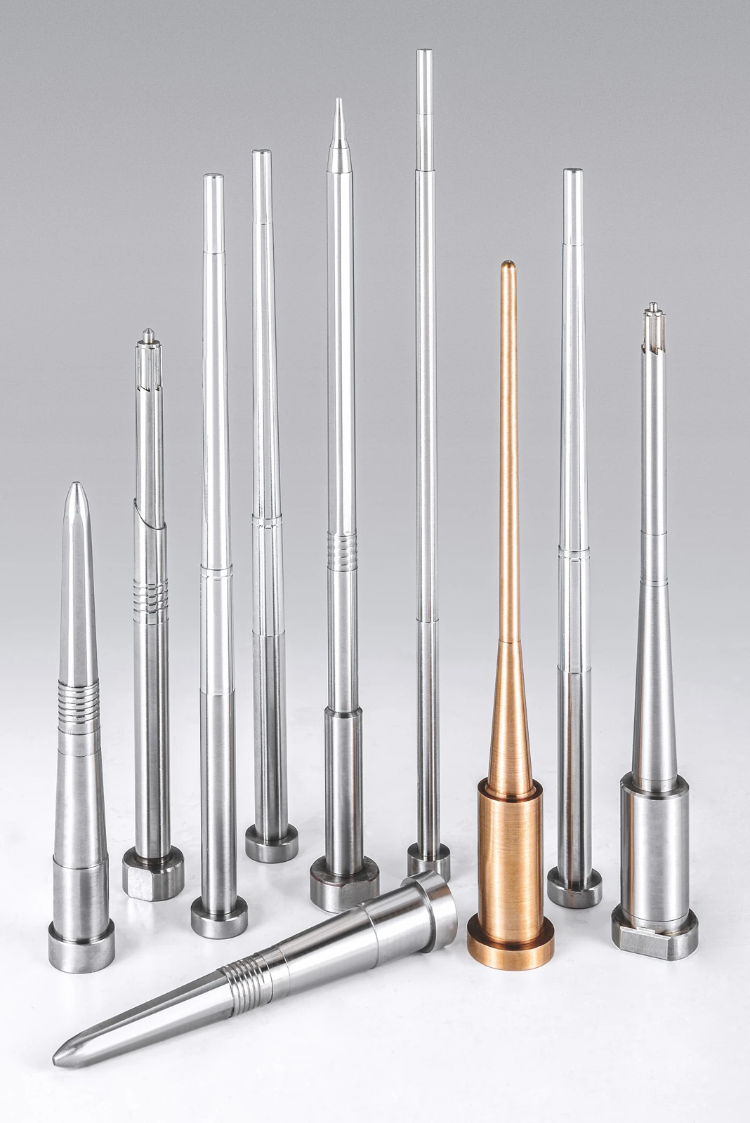 Product photograph showing slender metal mold component examples with stepped and tapered profiles